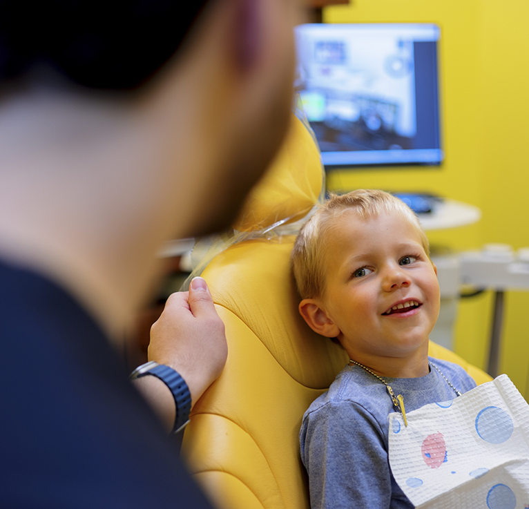 Little boy in dental chair looking up at pediatric dentist