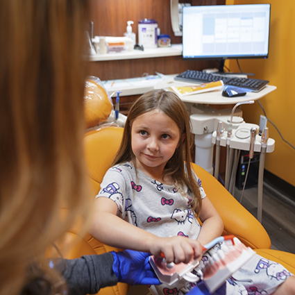 Little girl in dental chair looking up at dentist