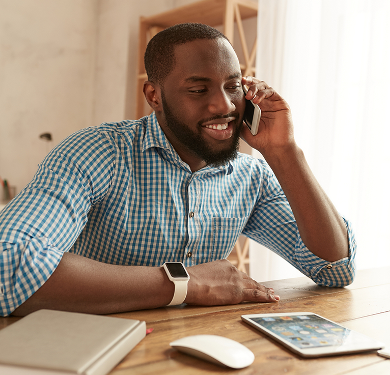 Smiling man sitting at desk and talking on phone