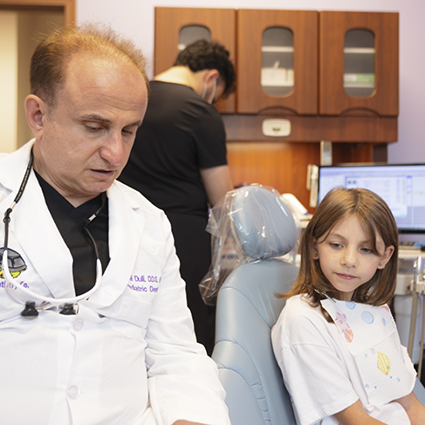 Pediatric dentist in Naperville talking to little girl in dental chair