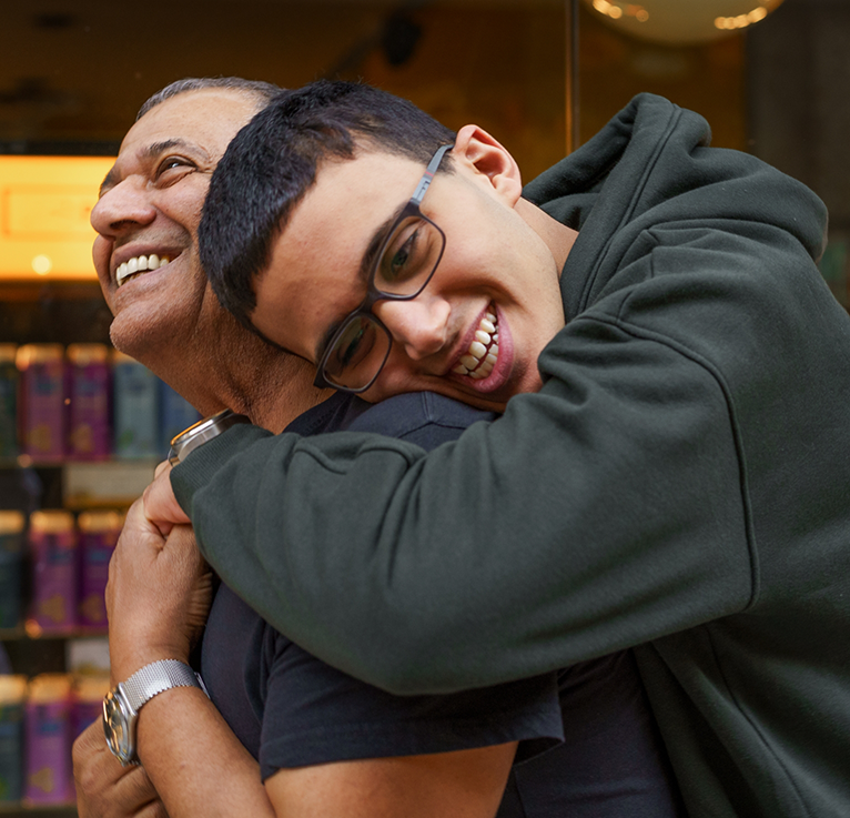 Child with glasses hugging parent from behind