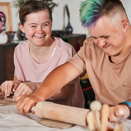 Two children with special needs flattening dough with rolling pins