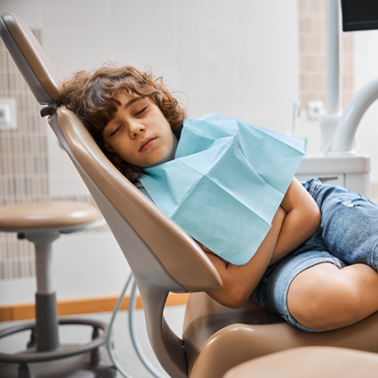 Young child relaxing in dental chair with eyes closed