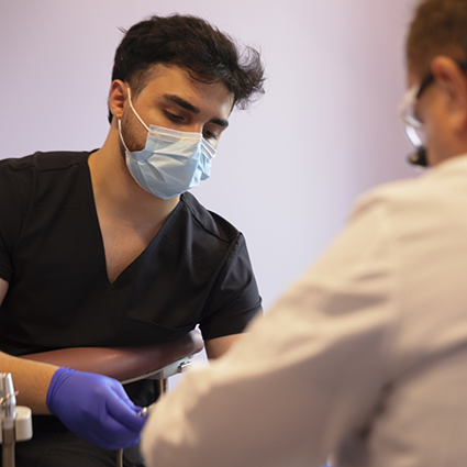 Dental team member with mask treating a patient