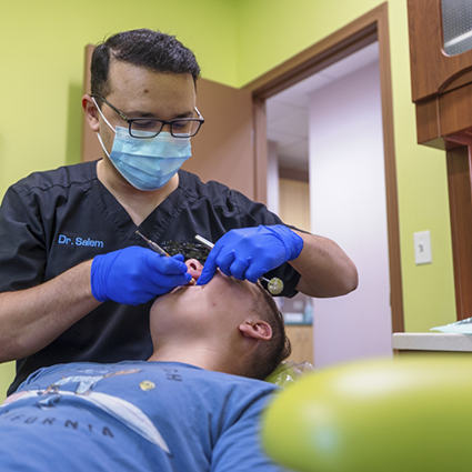 Pediatric dentist with mask treating teenage patient