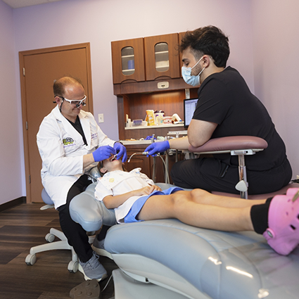 Pediatric dentist and team member treating patient