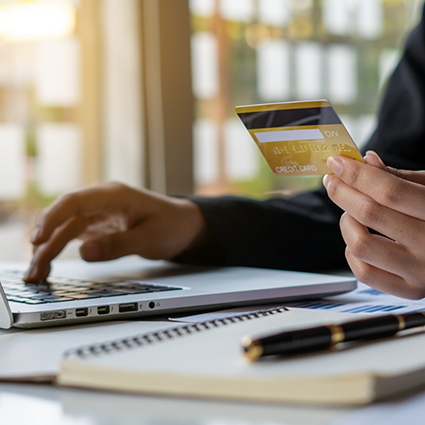 Typing on laptop and holding credit card