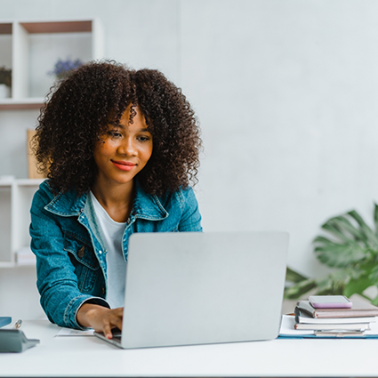 Woman with curly hair typing on laptop