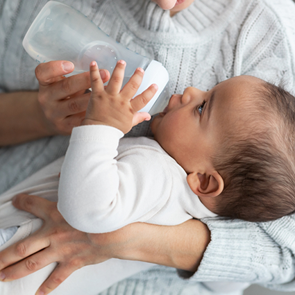 Baby drinking from bottle while held by mother