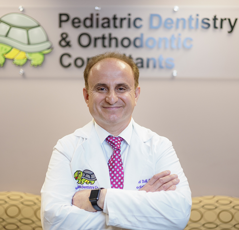 Naperville pediatric dentist Dr. Dulli smiling with arms folded