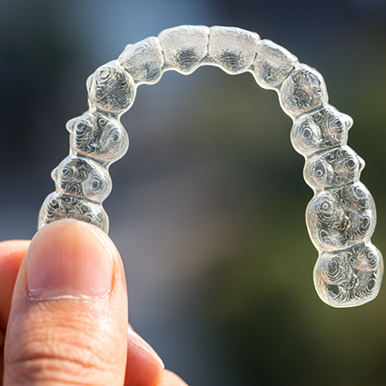 Close up of hand holding Invisalign clear aligner