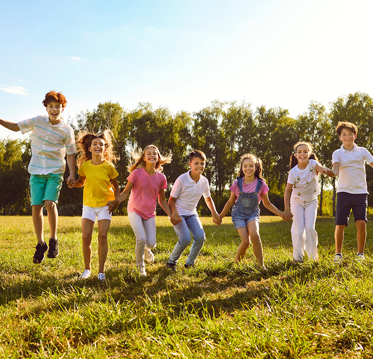 Smiling kids holding hands in a line outside