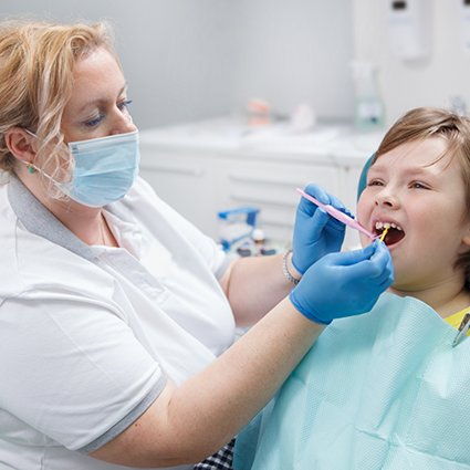 Female dentist applying silver diamine fluoride to little boy's teeth