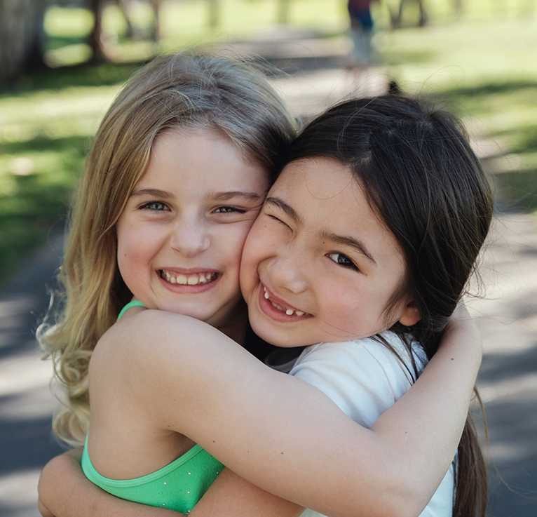 Two little girls smiling and hugging